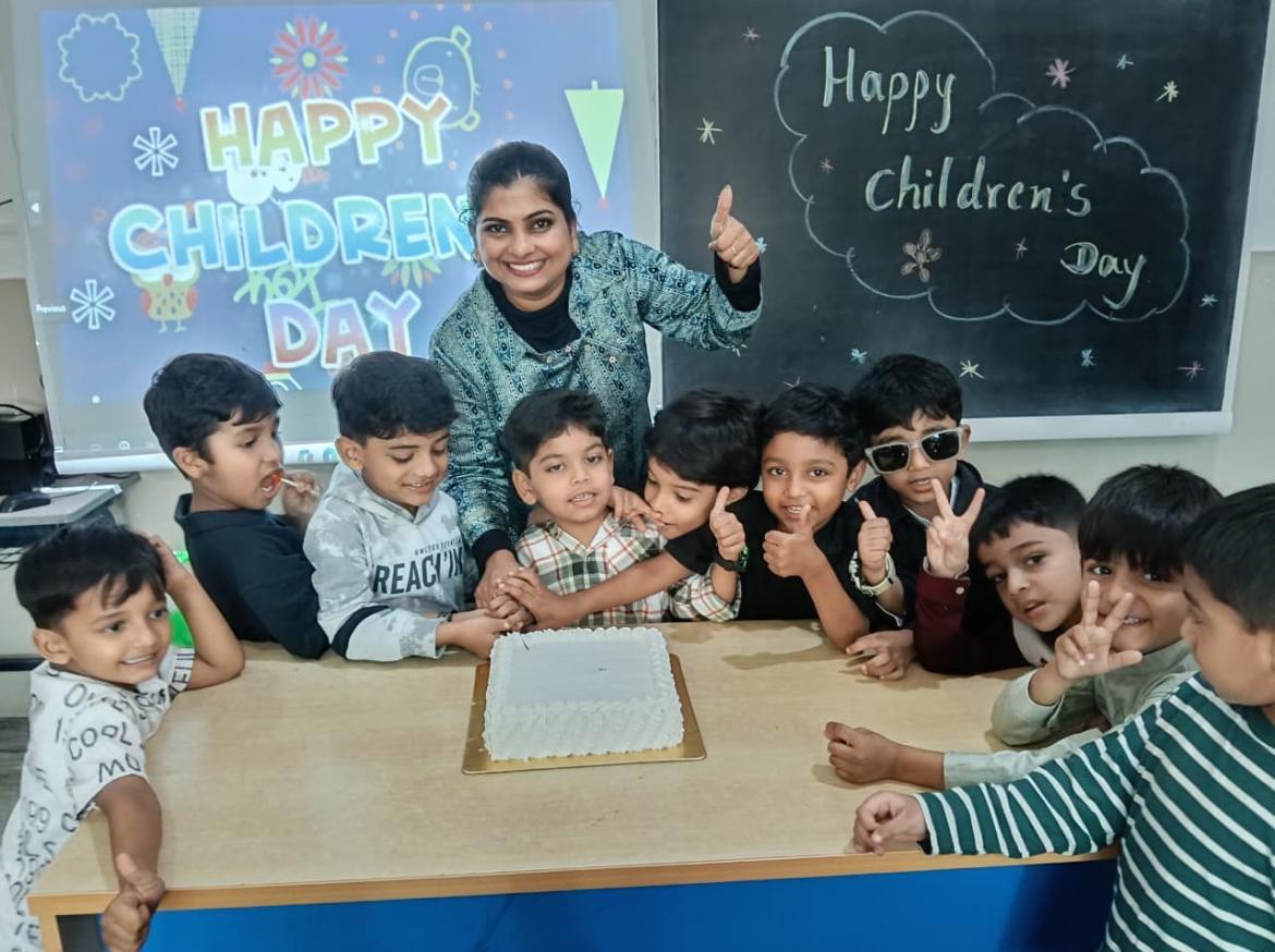 Teacher and young students celebrating together with a cake in a classroom
